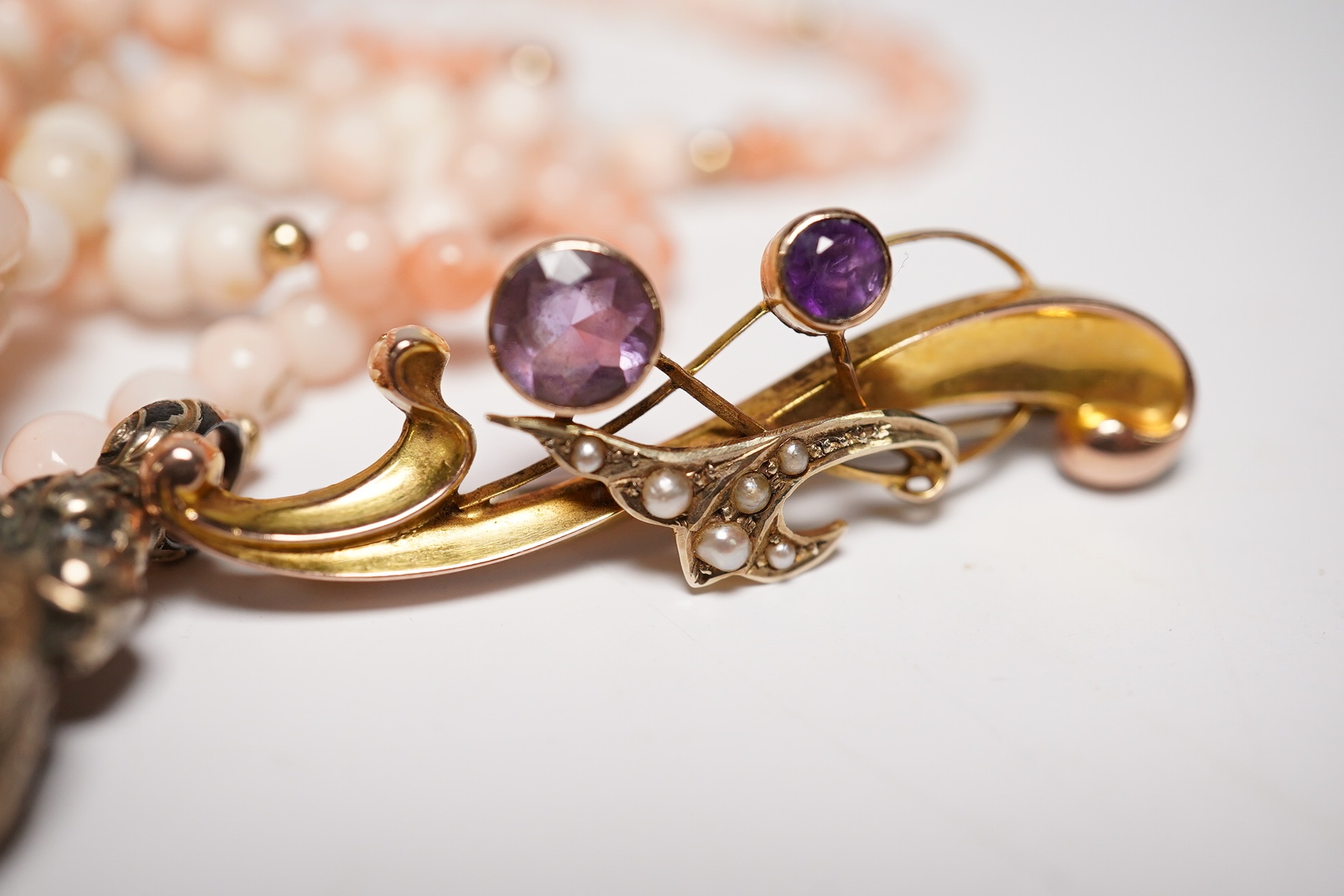An Edwardian 9ct gold and gen set scroll brooch, 40mm, a yellow metal and gem set ring, a yellow metal overlaid fob seal and a modern coral bead necklace. Condition - poor to fair